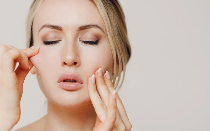femme qui pince son visage pour estimer la fermeté de sa peau