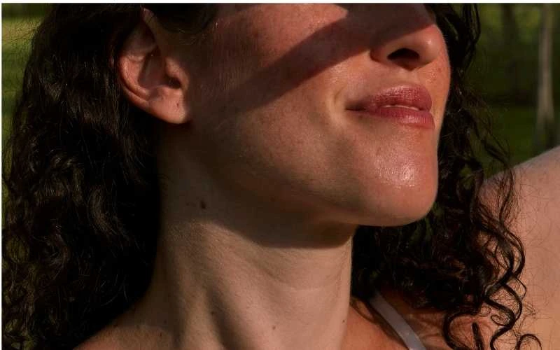 visage d'une femme qui se protège du soleil illustre les méfaits du soleil sur la peau.