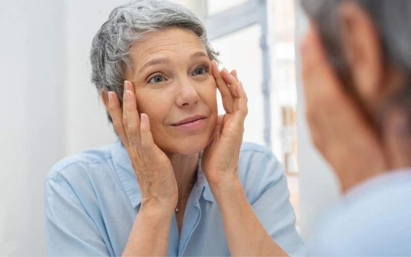 femme qui regarde le vieillissemnt de sa peau dans un miroir