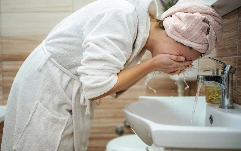 femme qui se nettoie le visage avec de l'eau